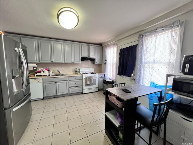 kitchen featuring backsplash, stainless steel appliances, sink, light tile patterned floors, and gray cabinets