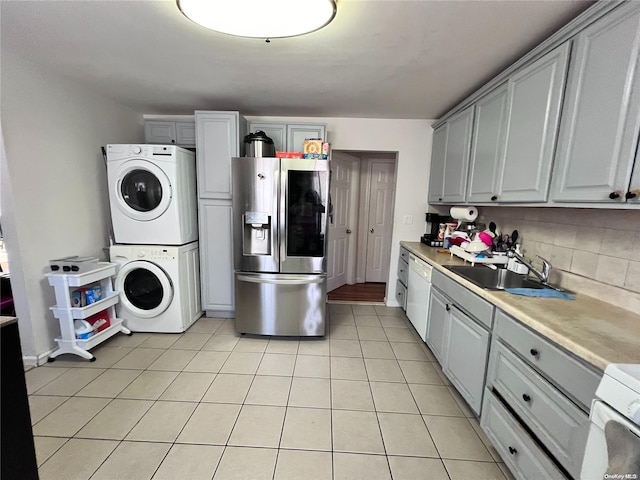 kitchen with white appliances, sink, gray cabinets, light tile patterned floors, and stacked washer / drying machine