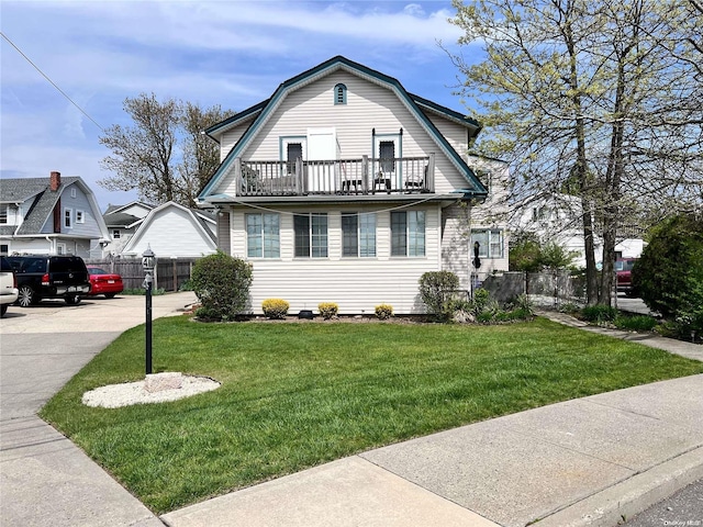 view of front facade with a balcony and a front lawn