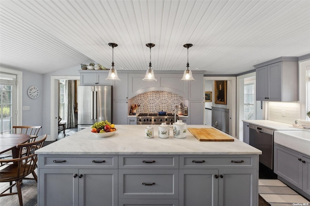 kitchen with gray cabinetry, decorative backsplash, pendant lighting, and stainless steel appliances