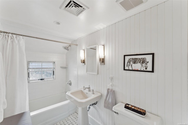 bathroom with toilet, shower / bathtub combination with curtain, and wood walls