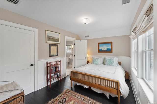 bedroom with ensuite bathroom and dark hardwood / wood-style floors