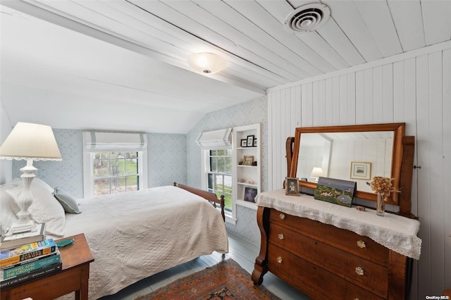 bedroom featuring wood walls, hardwood / wood-style floors, and vaulted ceiling