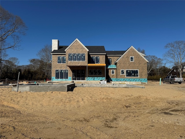 back of property with stone siding and a chimney