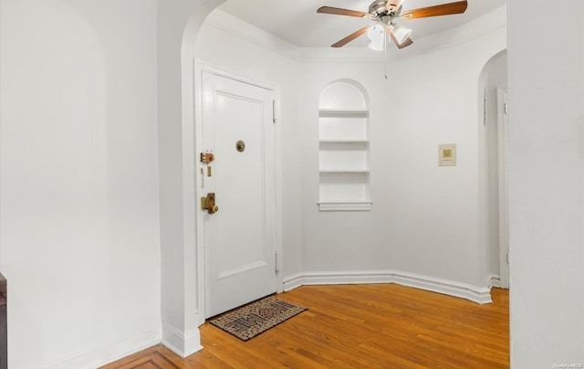 entrance foyer with hardwood / wood-style floors, ceiling fan, and ornamental molding