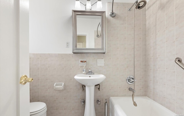 bathroom with tiled shower / bath, toilet, and tile walls