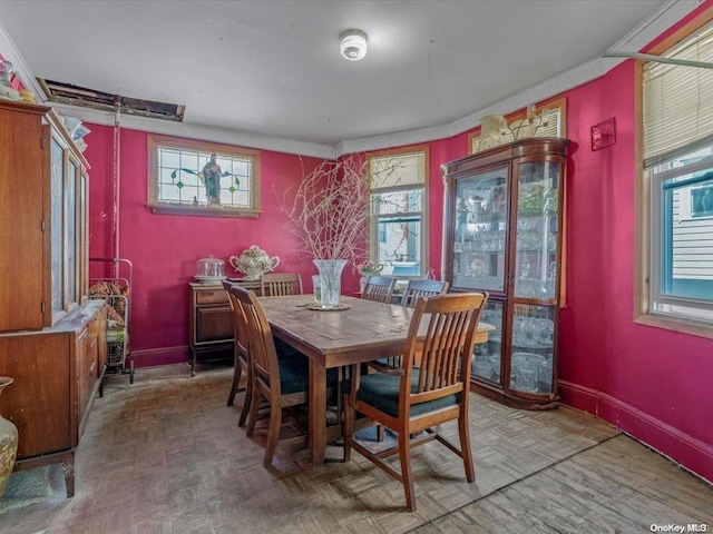 dining room featuring crown molding, a healthy amount of sunlight, and parquet flooring