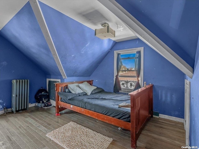 bedroom with radiator heating unit, vaulted ceiling, and hardwood / wood-style flooring