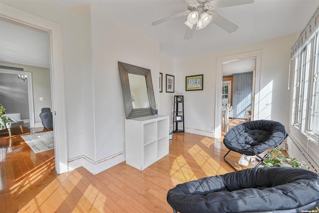 living area with light hardwood / wood-style floors, a wealth of natural light, and ceiling fan