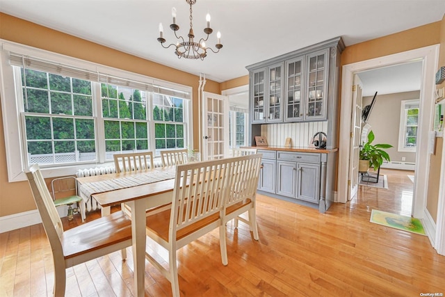 dining room featuring a wealth of natural light, a chandelier, a baseboard heating unit, and light wood-type flooring