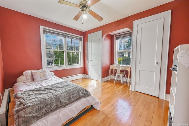 bedroom featuring baseboard heating, ceiling fan, and light hardwood / wood-style floors