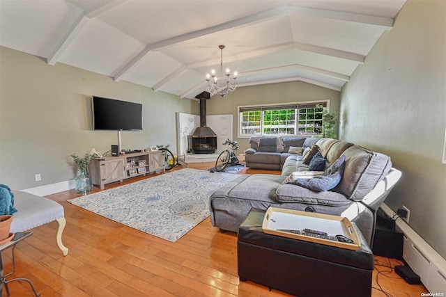 living room with vaulted ceiling with beams, light hardwood / wood-style floors, a wood stove, and an inviting chandelier