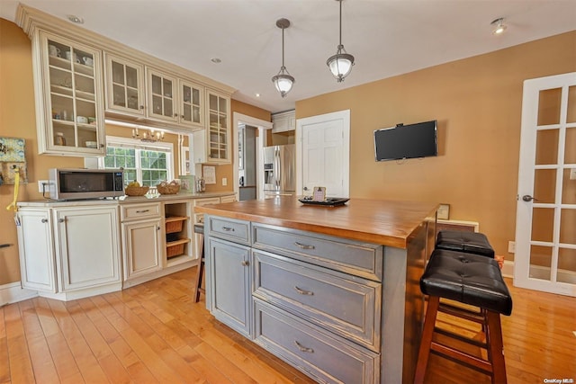 kitchen with gray cabinetry, light hardwood / wood-style flooring, decorative light fixtures, and appliances with stainless steel finishes