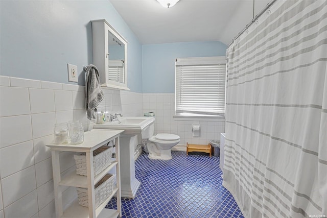 bathroom featuring tile patterned floors, toilet, sink, and tile walls