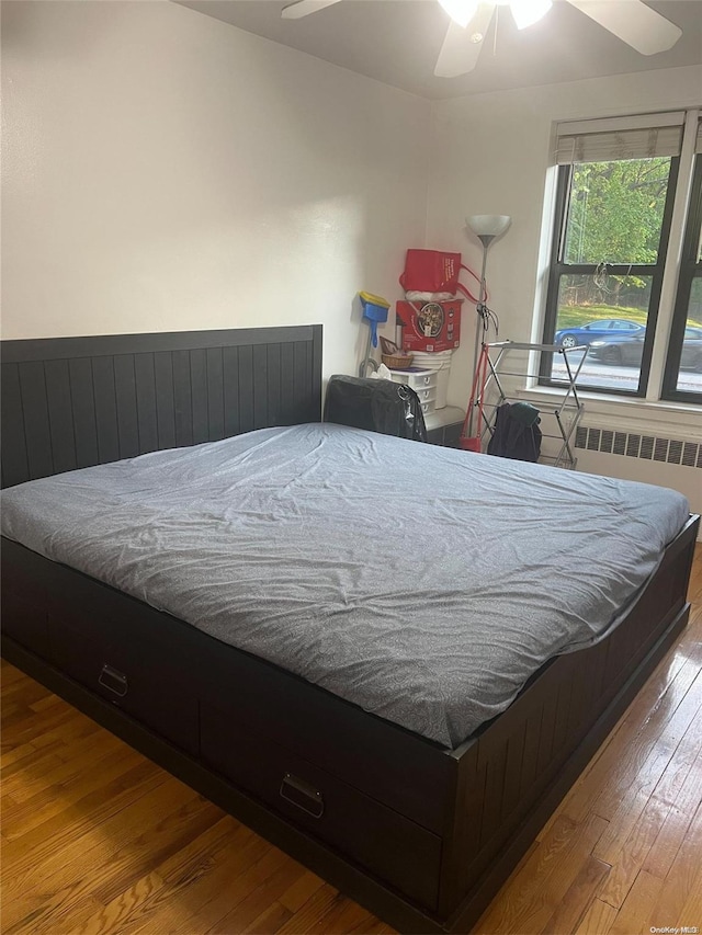 bedroom featuring ceiling fan, radiator heating unit, and light hardwood / wood-style floors