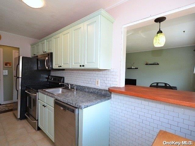 kitchen with white cabinetry, sink, decorative light fixtures, light tile patterned floors, and appliances with stainless steel finishes