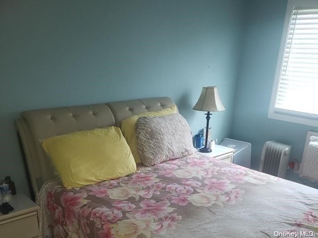 bedroom featuring radiator heating unit and multiple windows