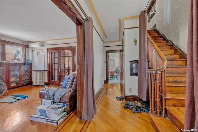 interior space featuring a wall mounted air conditioner, hardwood / wood-style floors, radiator heating unit, and crown molding