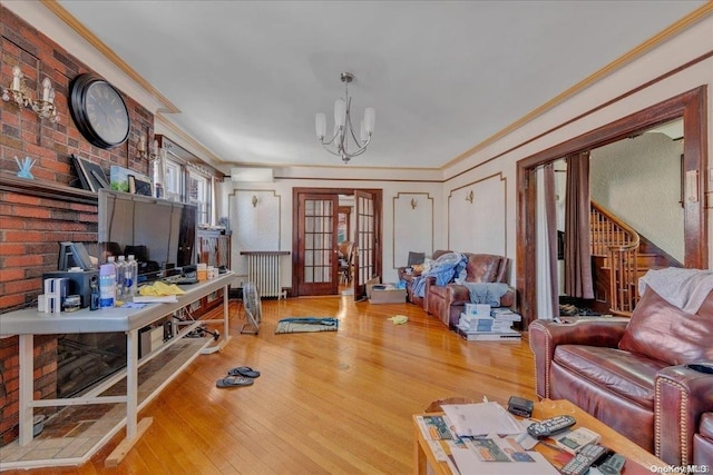 living room featuring radiator heating unit, french doors, an inviting chandelier, hardwood / wood-style flooring, and ornamental molding