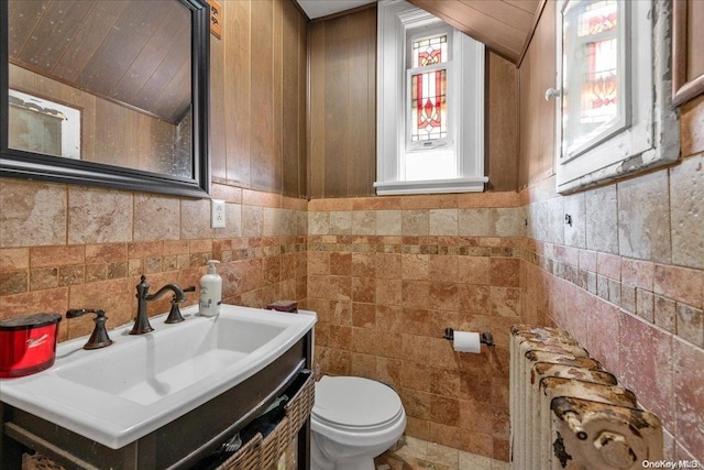 bathroom with radiator heating unit, vanity, toilet, and tile walls