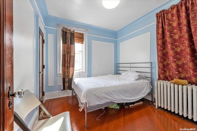 bedroom with hardwood / wood-style floors and radiator