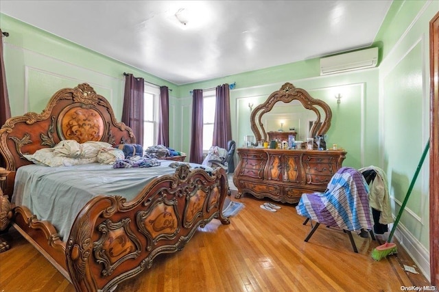 bedroom featuring wood-type flooring and a wall mounted air conditioner