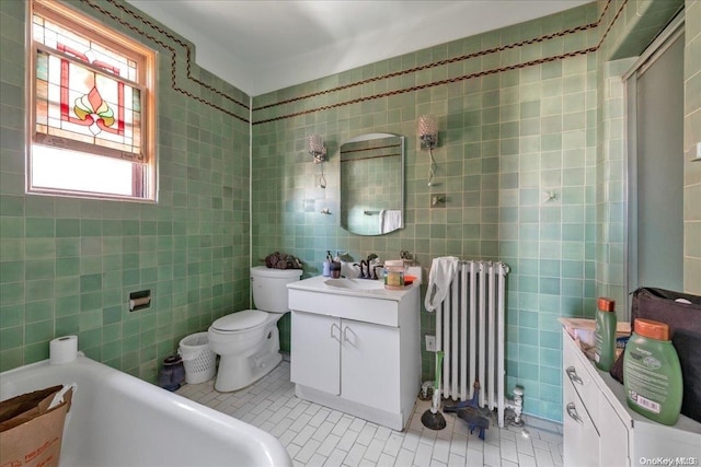 bathroom with radiator, tile patterned floors, toilet, vanity, and tile walls