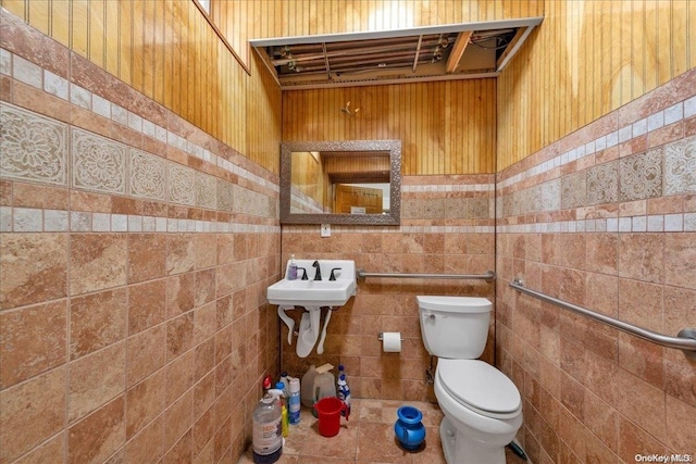 bathroom with sink, toilet, and tile walls