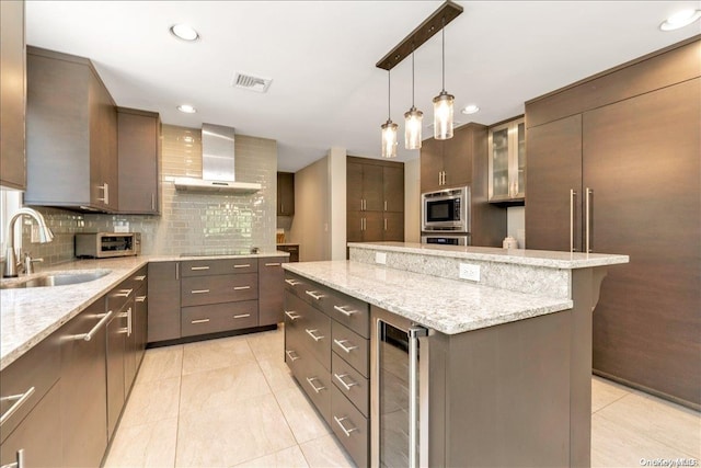 kitchen featuring sink, wall chimney exhaust hood, wine cooler, built in appliances, and decorative backsplash