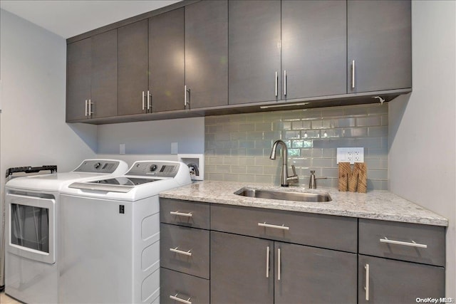 washroom with cabinets, washing machine and dryer, and sink