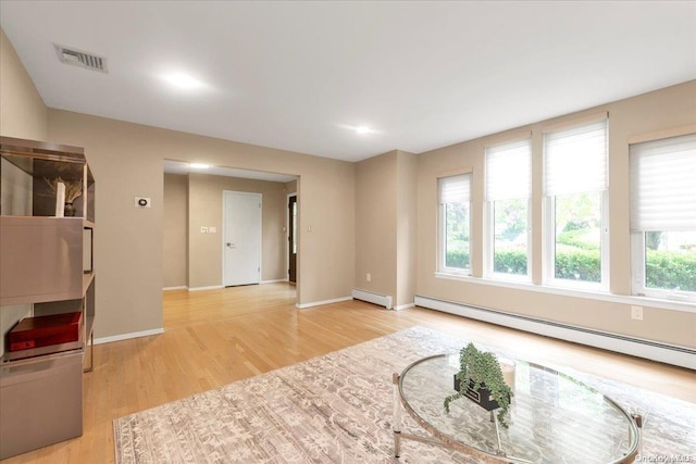 living area with plenty of natural light, a baseboard radiator, and light hardwood / wood-style flooring