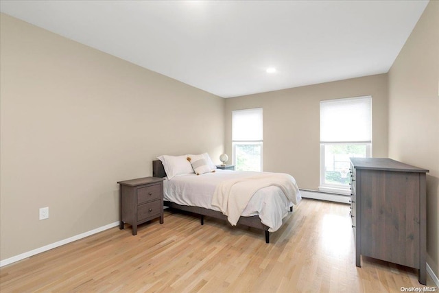 bedroom with light wood-type flooring and a baseboard radiator