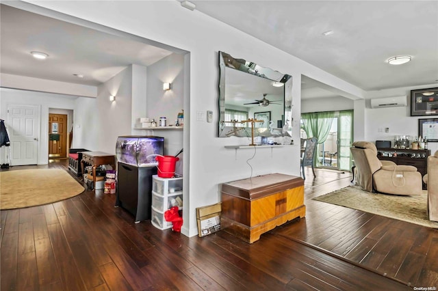 living room with hardwood / wood-style floors, a wall unit AC, and ceiling fan