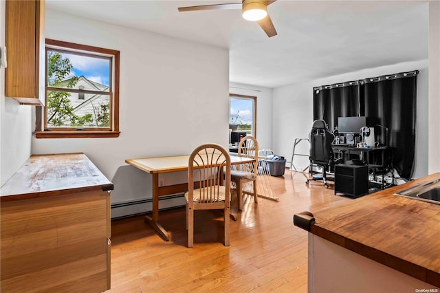 dining room with ceiling fan, light hardwood / wood-style floors, and a baseboard heating unit