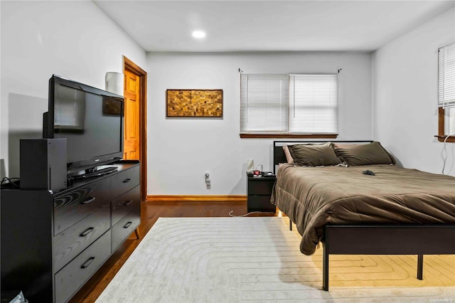 bedroom with dark hardwood / wood-style floors and multiple windows