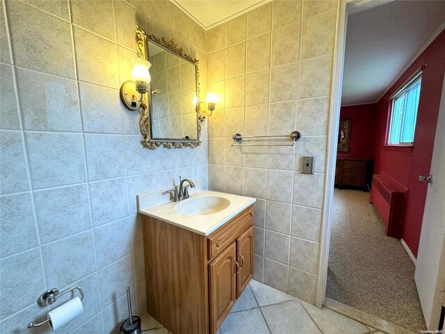 bathroom featuring tile patterned floors, radiator, vanity, and tile walls