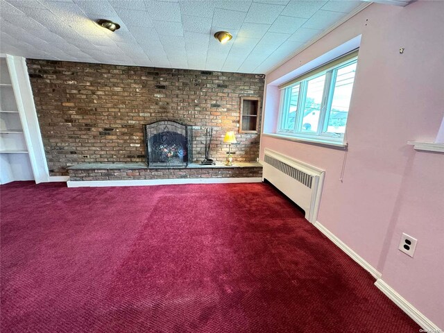 unfurnished living room featuring radiator heating unit, carpet floors, brick wall, and a brick fireplace