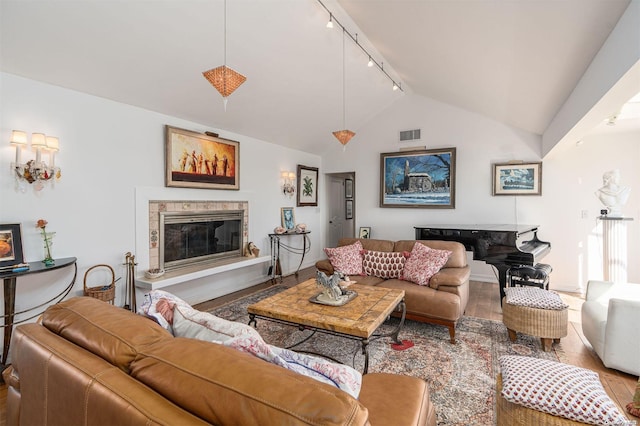 living room featuring hardwood / wood-style floors, rail lighting, and vaulted ceiling