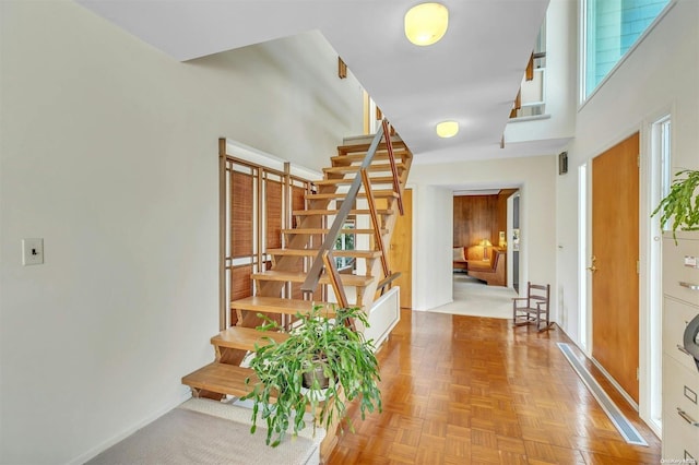 foyer entrance with a towering ceiling and parquet floors