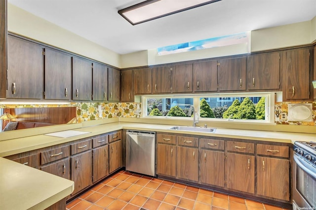 kitchen with sink, light tile patterned floors, appliances with stainless steel finishes, tasteful backsplash, and dark brown cabinetry