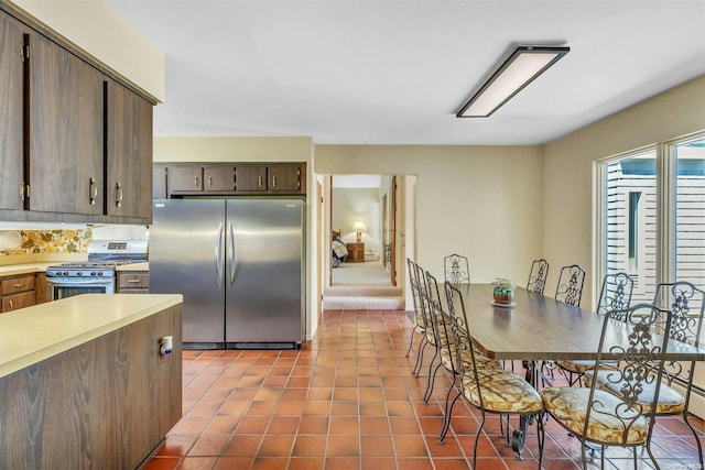 kitchen with dark brown cabinetry, light tile patterned floors, stainless steel appliances, and tasteful backsplash