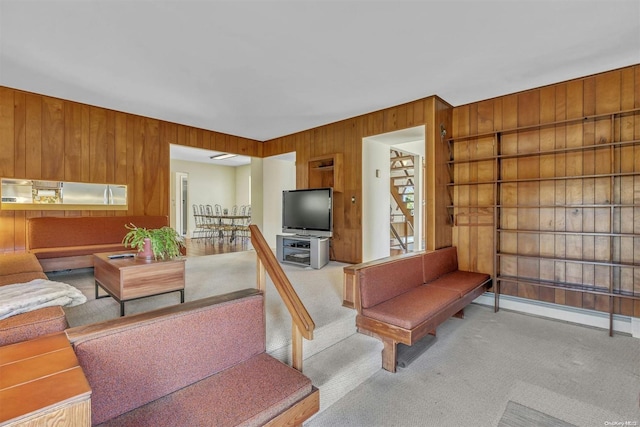 carpeted living room featuring wood walls