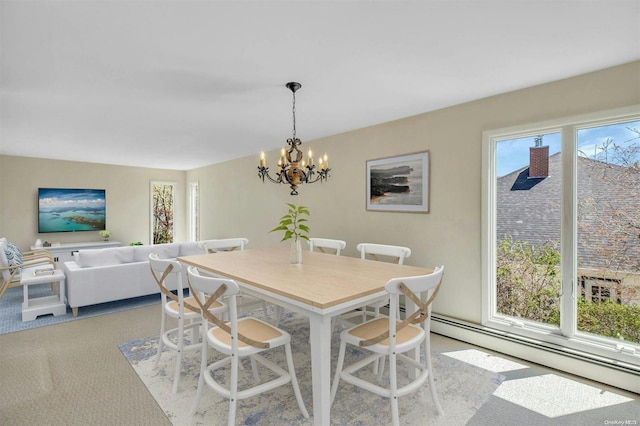 carpeted dining area with a chandelier and a baseboard heating unit