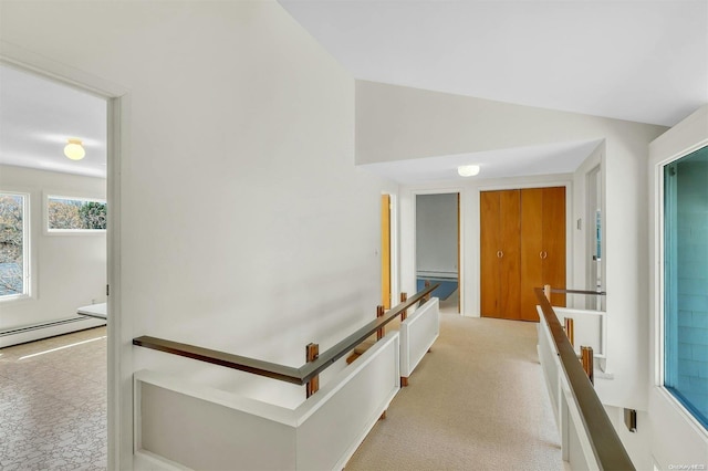 hall with vaulted ceiling, light colored carpet, and a baseboard heating unit