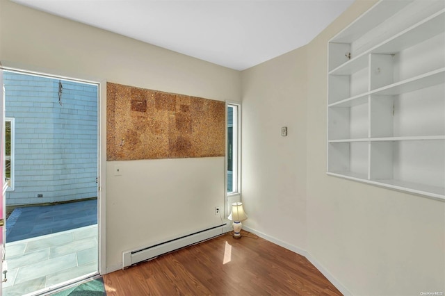 unfurnished room with hardwood / wood-style flooring and a baseboard heating unit