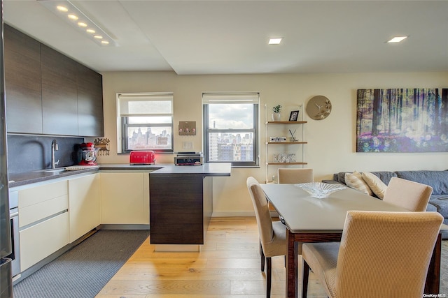 kitchen with light hardwood / wood-style floors, white cabinetry, and sink