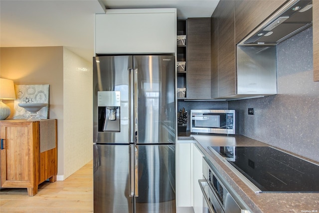 kitchen with stainless steel appliances, premium range hood, light hardwood / wood-style floors, decorative backsplash, and white cabinets