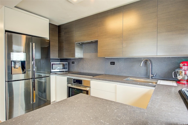 kitchen featuring backsplash, sink, stainless steel appliances, and ventilation hood