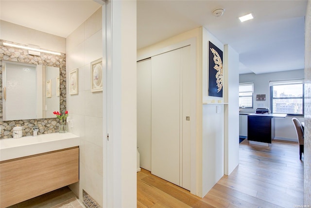 bathroom with hardwood / wood-style floors, vanity, and tile walls