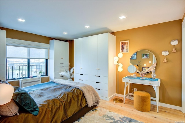 bedroom with light hardwood / wood-style floors and a wall unit AC